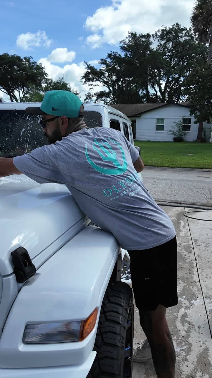 Olympus detailer in a trident tee foaming a white Jeep